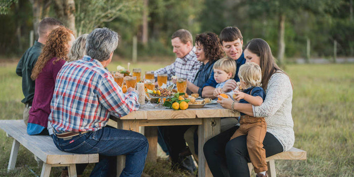 Register Family sitting at picnic table having dinner together.
