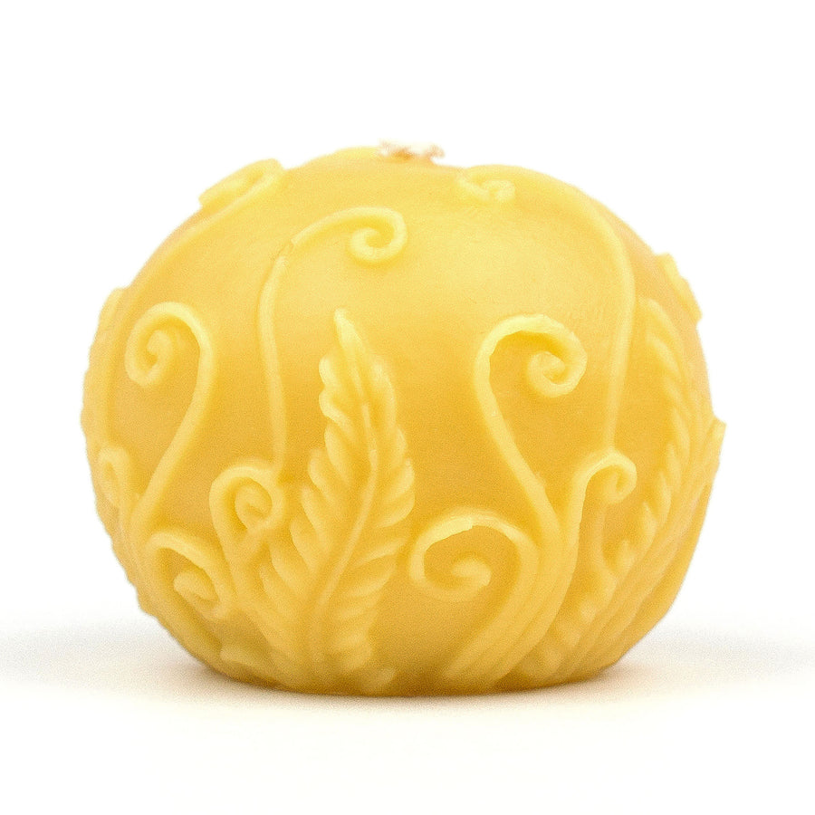 Round beeswax candle with fern pattern.