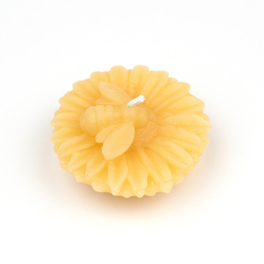 Floating flower-shaped beeswax votive with bee.